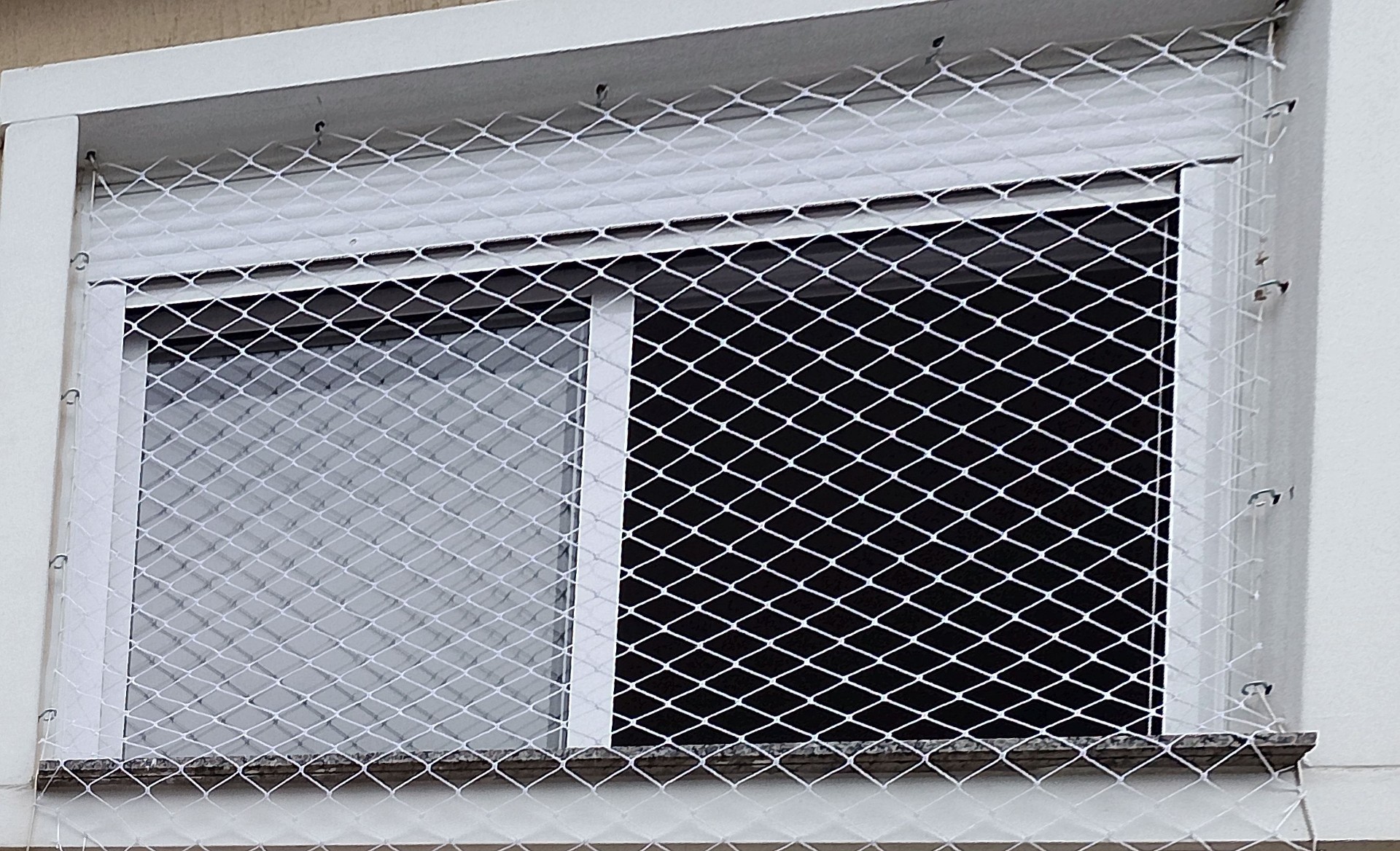 Janela externa com rede branca de proteção