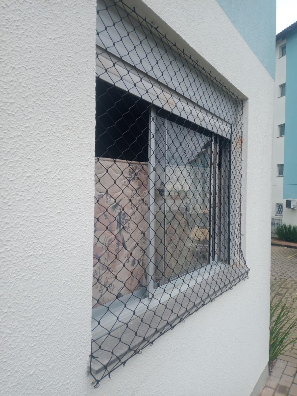 Janela de apartamento com rede preta de proteção