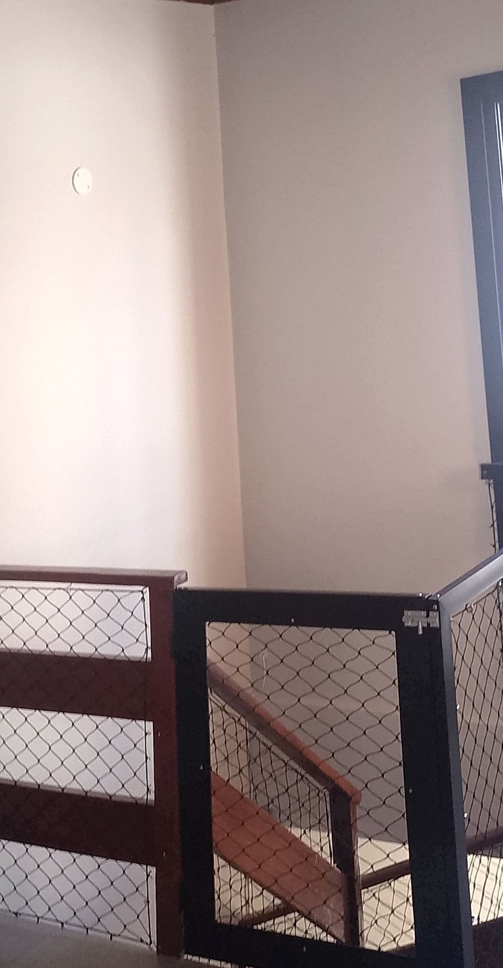 Mezanino com guarda-corpo em madeira e rede de proteção entre os vãos