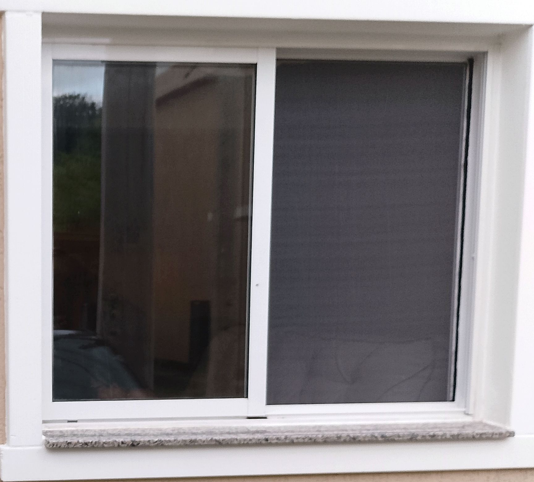 Janela de correr branca com tela mosqueteira instalada