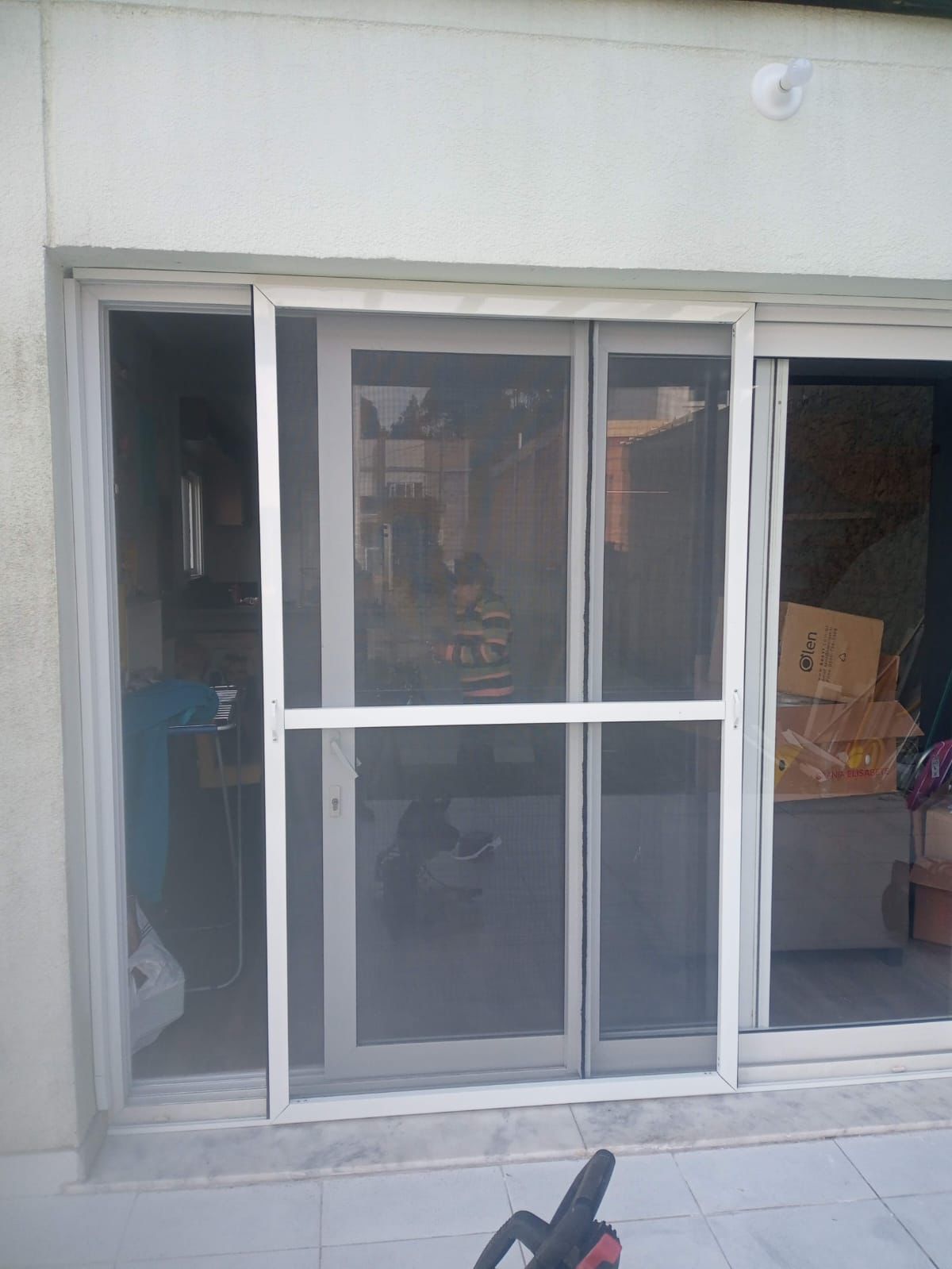 Porta de correr ampla com tela mosqueteira branca instalada