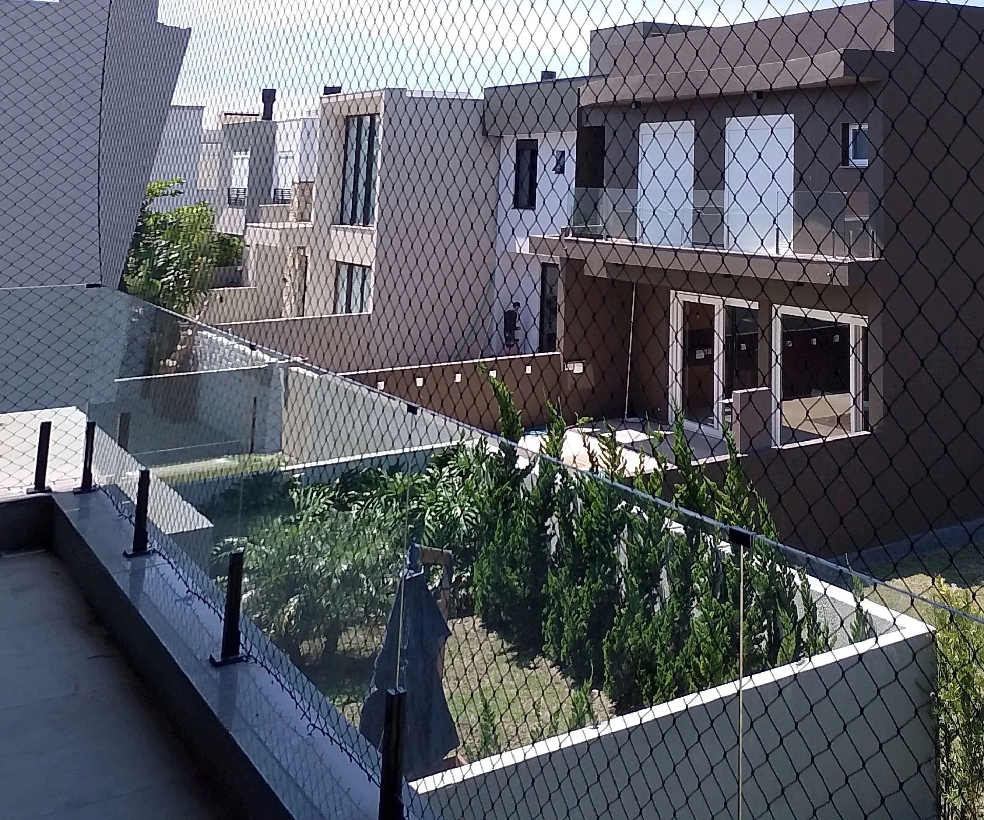 Sacada com rede de proteção preta e vista para casas do condomínio