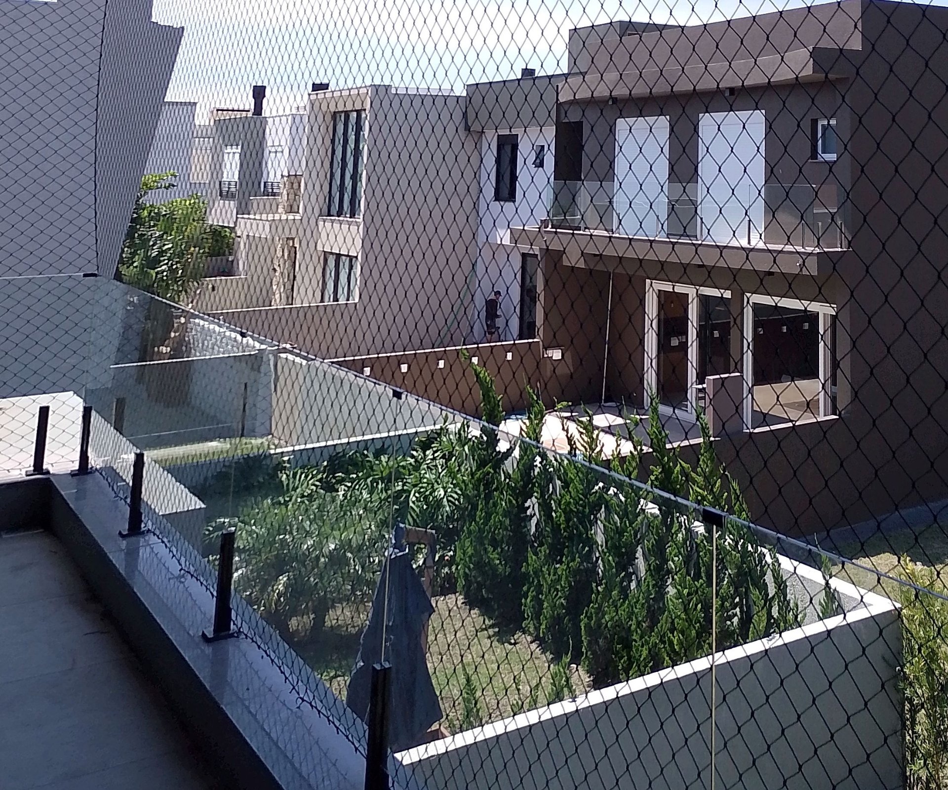 Sacada com rede de proteção preta e vista para casas do condomínio