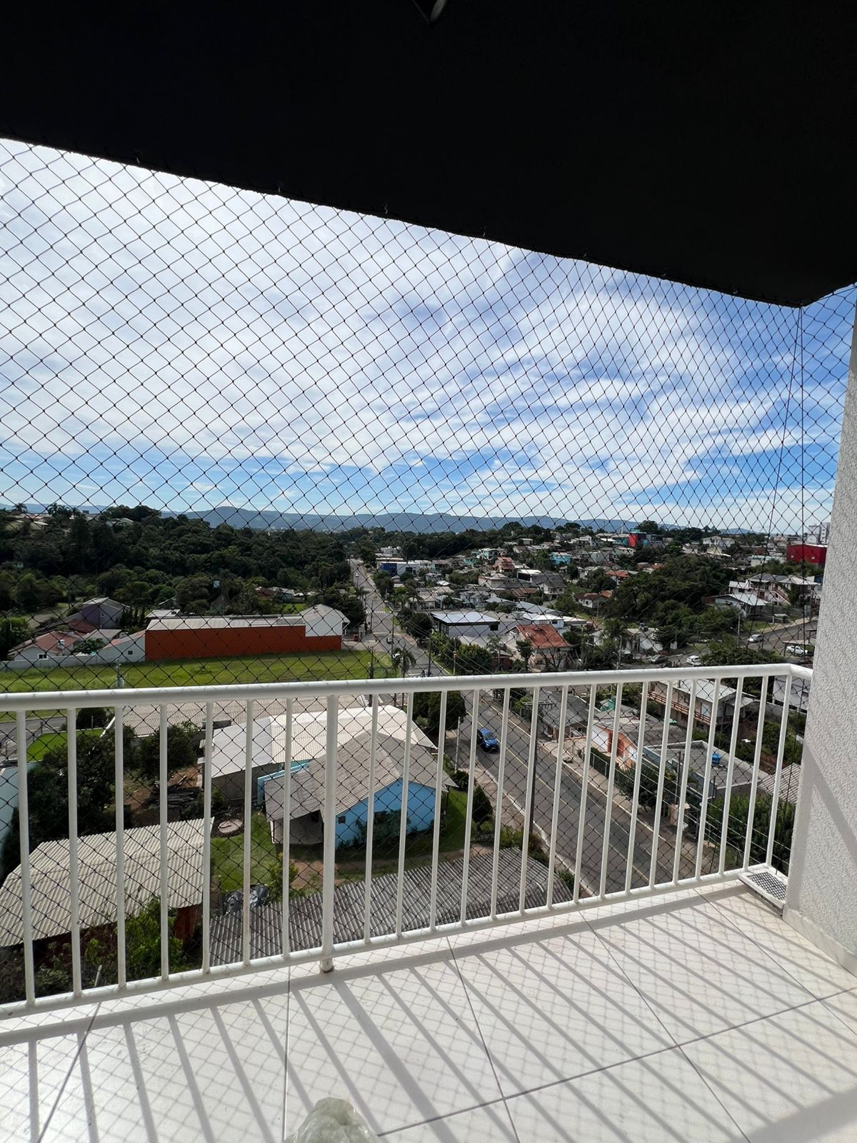 Sacada de apartamento com rede preta e vista panorâmica da cidade