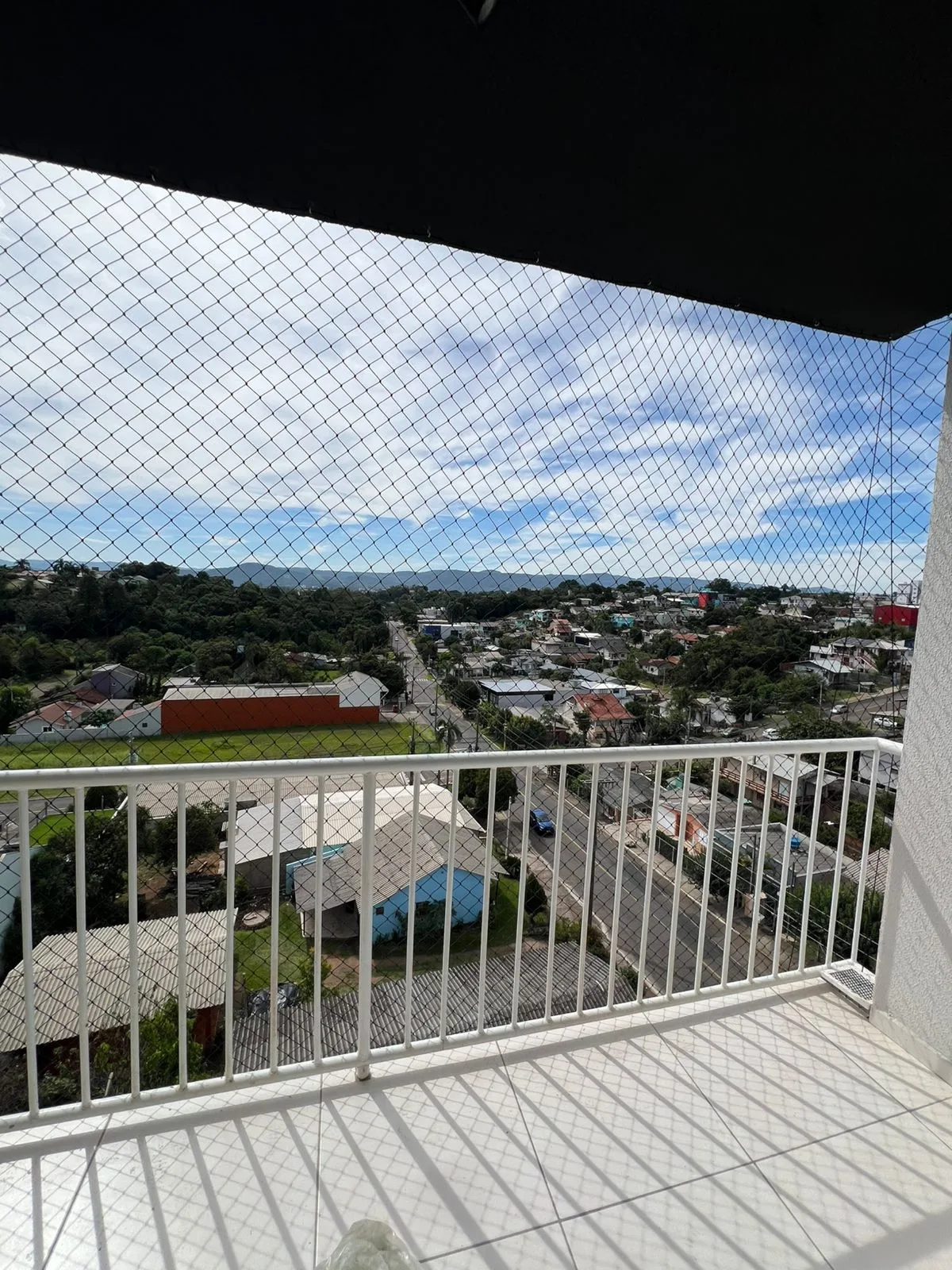Sacada de apartamento com rede preta e vista panorâmica da cidade