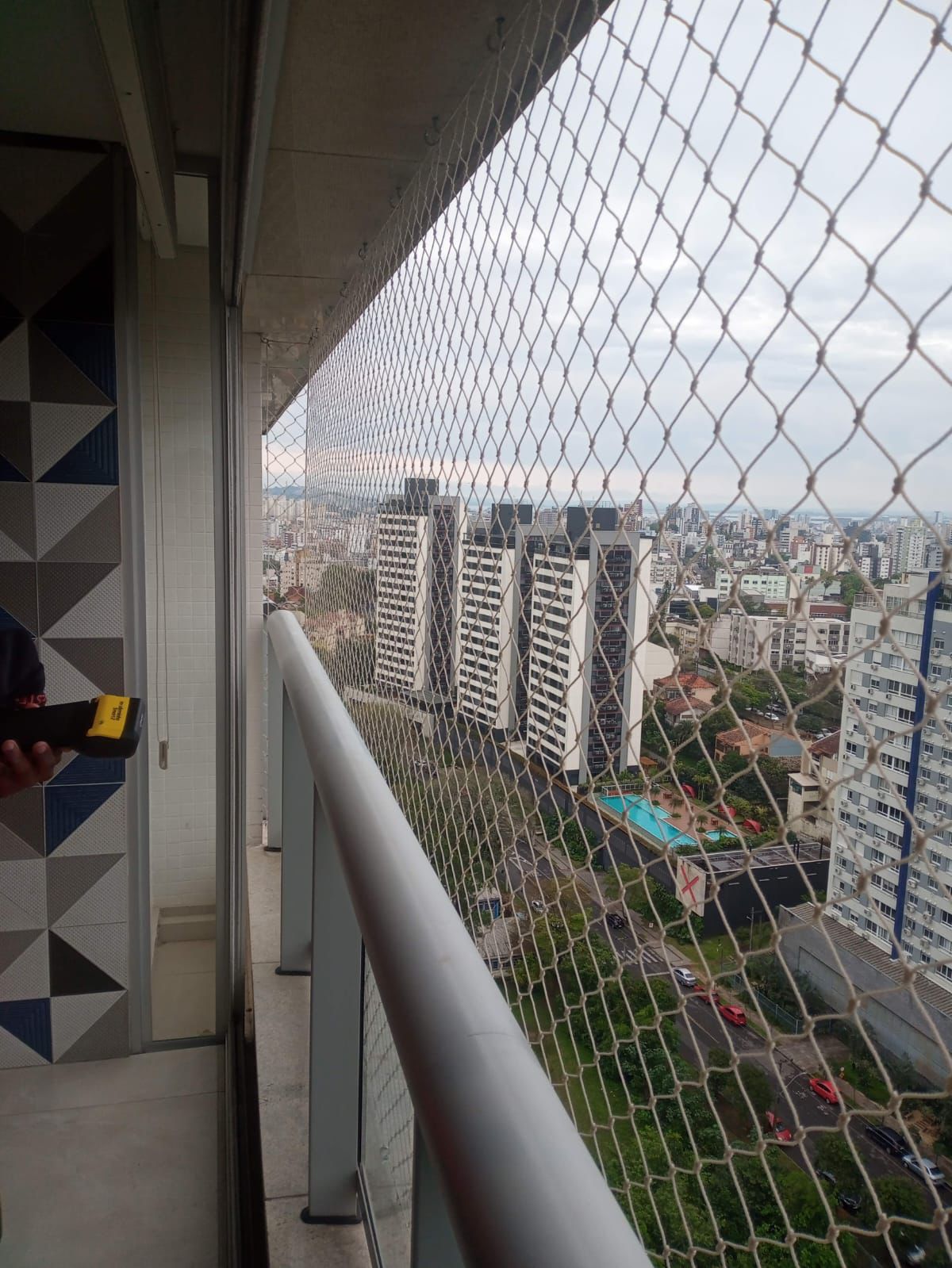 Sacada de cobertura com rede branca e vista para o centro de Porto Alegre
