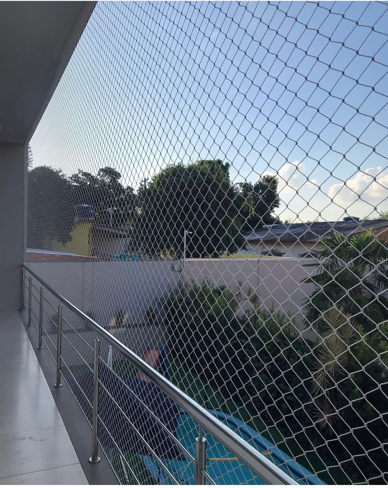 Sacada com guarda-corpo de inox e rede de proteção branca