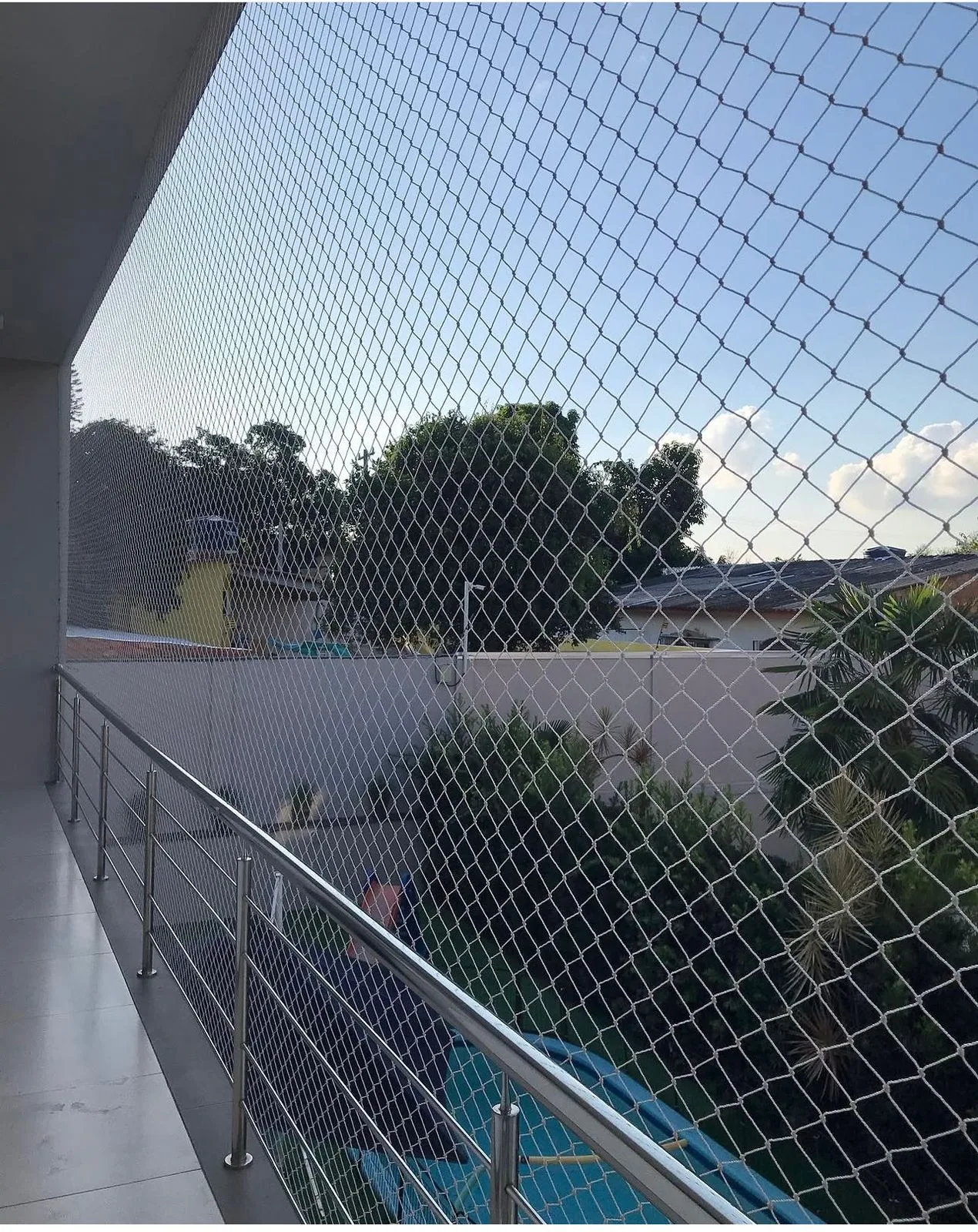 Sacada com guarda-corpo de inox e rede de proteção branca