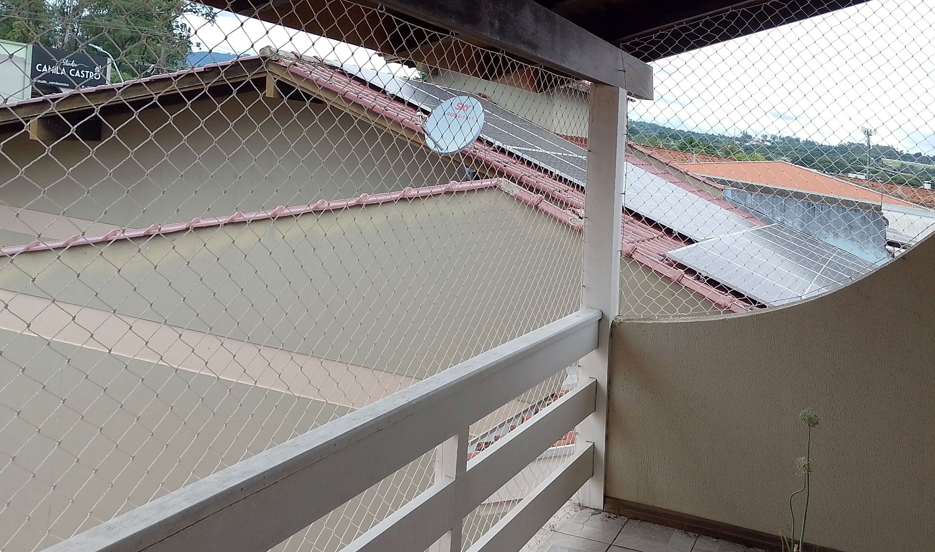 Sacada com guarda-corpo de madeira e rede branca de proteção